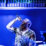Marcin, wokalista zespołu GMOH, wykonuje utwór podczas koncertu w klubie Alive we Wrocławiu. Niebieskie światło sceniczne, dynamiczna poza i ekspresyjny śpiew oddają energię występu blackened death metalowej formacji.