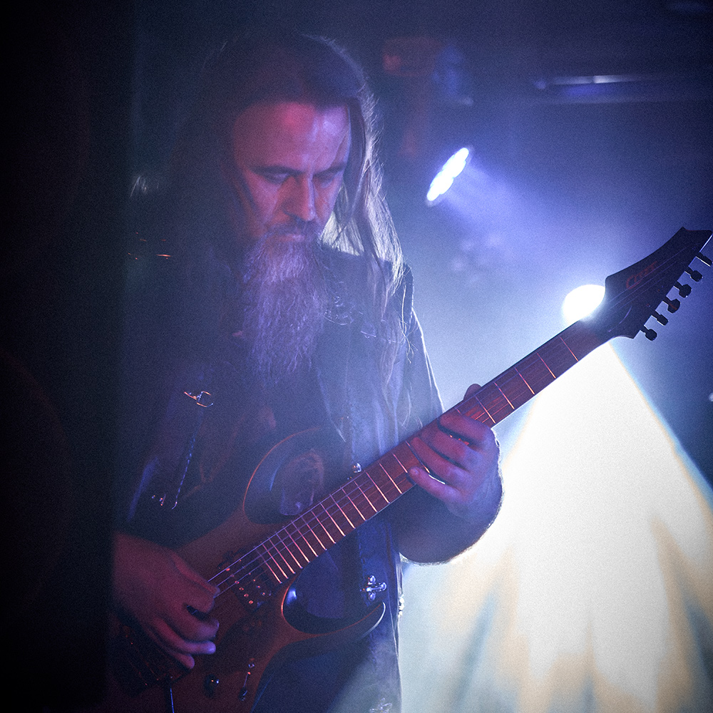 Niko Woodward, gitarzysta Vae Solis, podczas koncertu we Wrocławiu w ramach wydarzenia „Brudna Odra”, grający na gitarze w niebiesko-białym świetle scenicznych reflektorów.