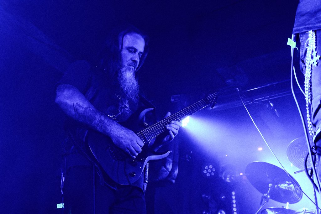 Niko Woodward, gitarzysta Vae Solis, podczas koncertu we Wrocławiu w ramach wydarzenia „Brudna Odra”, grający na gitarze w intensywnym niebieskim świetle sceny.