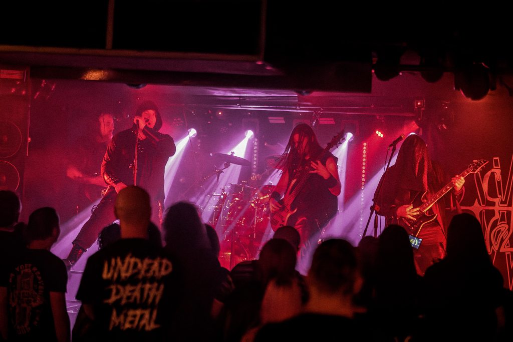 Vae Solis podczas koncertu we Wrocławiu w ramach wydarzenia „Brudna Odra” – cały zespół na scenie, z Inferatu, gitarzystami, basistą i perkusistą, przed publicznością w czerwonym i fioletowym świetle.