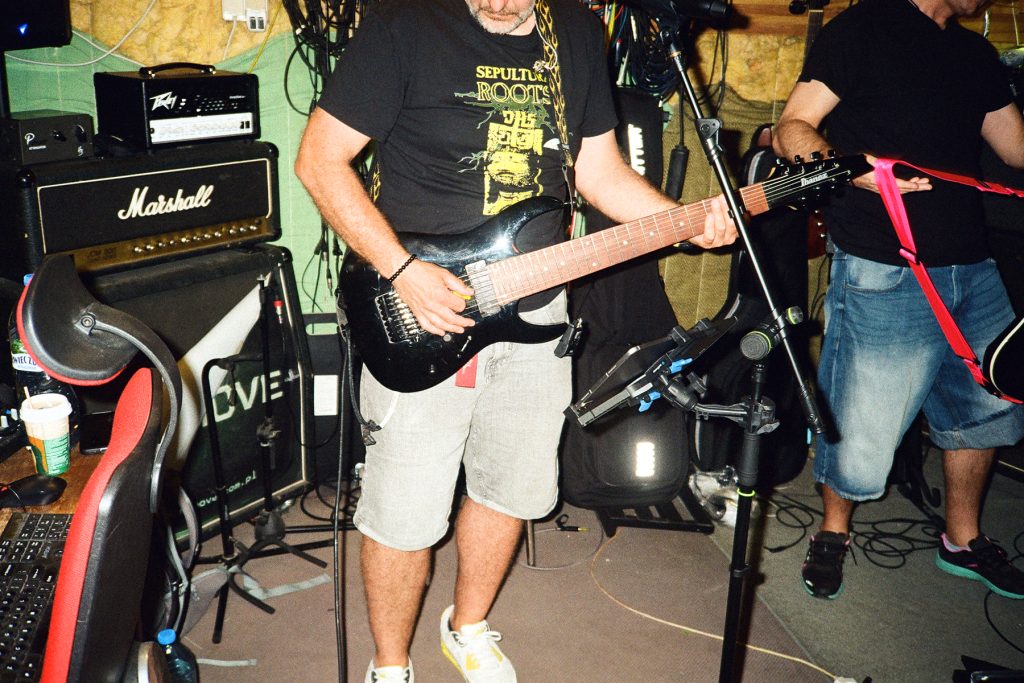 Snup grający na gitarze podczas próby zespołu Furydate, obok niego Max z gitarą w sali prób.